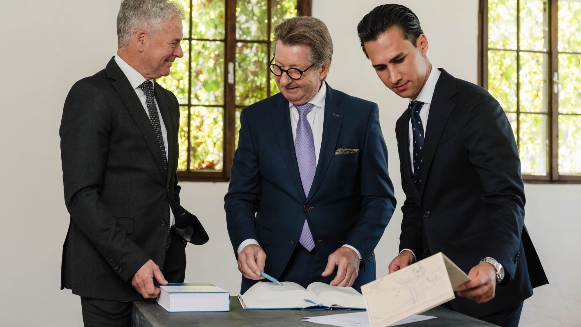 Besprechung in unserem Haus: drei Kollegen am Arbeitstisch mit Fachkommentar zur Wertermittlung und Lageplan